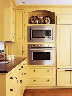 a kitchen with yellow painted cabinets and stainless steel appliances, including a built - in microwave