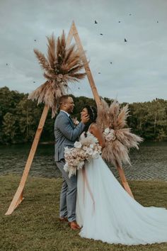 a man and woman standing next to each other in front of a body of water