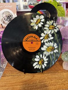 an old record with flowers painted on it sitting on a table next to other items