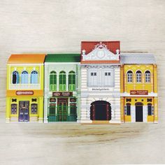 there are many different colored buildings on this wooden surface, one is painted yellow and the other is green