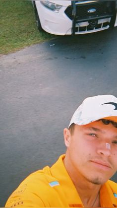 a man in yellow shirt and white hat next to a parked car on the street