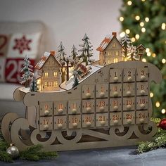 a wooden calendar with houses and trees on it next to a christmas ornament