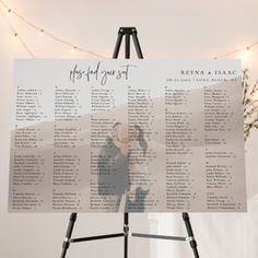 the seating chart for this wedding is displayed on a easel with lights in the background