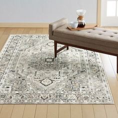 a beige bench sitting on top of a hard wood floor next to a white rug