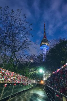 the walkway is lined with hundreds of padlocks and locks, along with an illuminated tower in the background