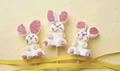 three bunny lollipops sitting on top of a yellow ribbon next to each other