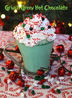 a green cup filled with whipped cream and sprinkles on top of a table