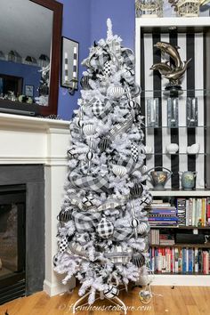 a christmas tree decorated with black and white ornaments in front of a book shelf filled with books