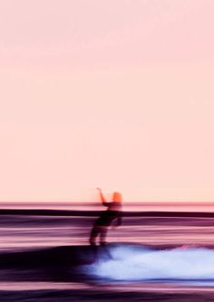 a man riding a wave on top of a surfboard in the ocean at sunset