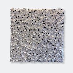 a piece of art that is made out of silver and white pebbles on a gray background