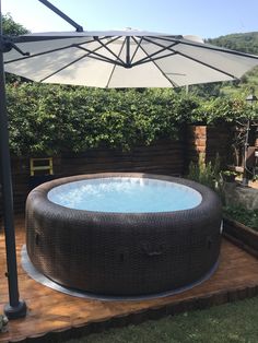 an inflatable hot tub sitting on top of a wooden deck next to a white umbrella