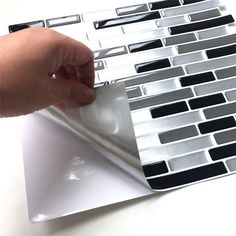 a hand is pressing buttons on a keyboard that has been made out of silver and black squares