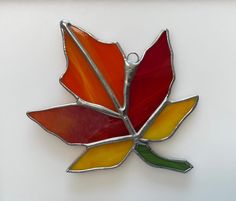 a stained glass leaf ornament hanging on a wall in the shape of a flower