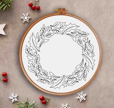 a cross stitch pattern with holly wreaths and snowflakes on the table next to it