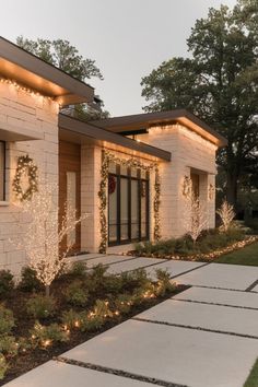 an exterior view of a modern home with lights on the front and side of the house