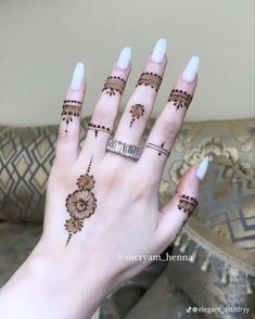 a woman's hand with henna tattoos and rings on her left hand,