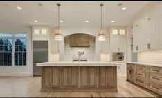 a large kitchen with an island in the middle and lots of cabinets on both sides