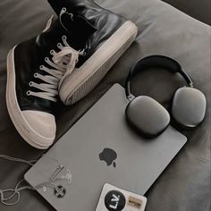 a pair of headphones, an apple laptop and ear buds are sitting on a bed