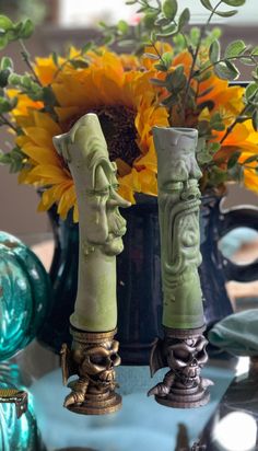 two vases with faces are sitting on a table next to sunflowers and other decorative items