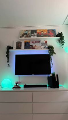 a white entertainment center with green lights and plants on the top shelf, along with bookshelves