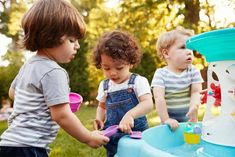 three young children playing in a water fountain