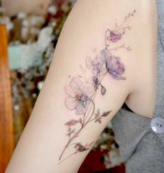 a close up of a person's arm with flowers tattooed on the back of it