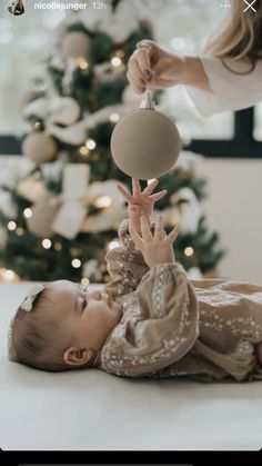 a baby laying on the floor playing with a ball while being held by a woman