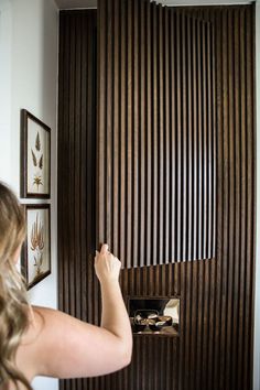 a woman is opening the door with her hand and looking at something on the wall