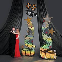 two people standing next to each other in front of black curtains with lights on them