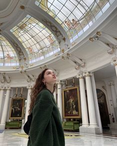 a woman looking up at the sky in a large room with paintings on the walls