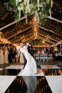 a bride and groom dance on the dance floor at their wedding reception in front of an audience