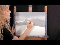 a woman is painting on an easel with white paint and she has long blonde hair