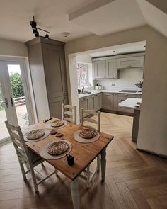 a wooden table topped with plates of food on top of a hard wood floored kitchen