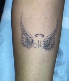 a tattoo on the leg of a person with wings and an angel halo above it