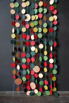 a multicolored mobile with circles hanging from it's sides on a black wall