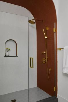 a bathroom with a walk in shower next to a white wall and brown tiled floor