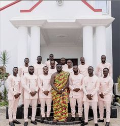 a group of men standing next to each other in front of a white building with red trim