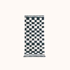 a black and white checkerboard towel hanging on a wall in front of a white background