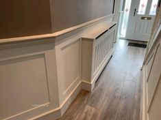 an empty hallway with wooden floors and white trim