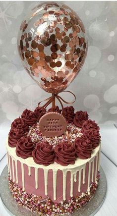 a birthday cake with chocolate frosting and pink icing on top, topped with a large balloon