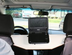 a laptop computer sitting on top of a desk in the back seat of a car