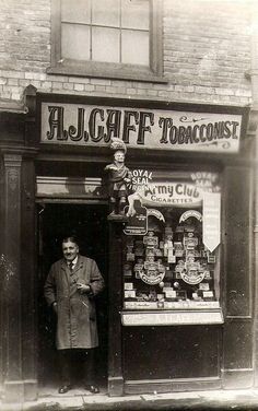 an old black and white photo of a man standing in front of a store