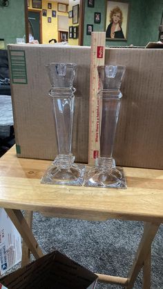 two clear vases sitting on top of a wooden table next to a cardboard box