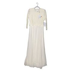 a white dress hanging on a hanger with an embroidered appliqued design