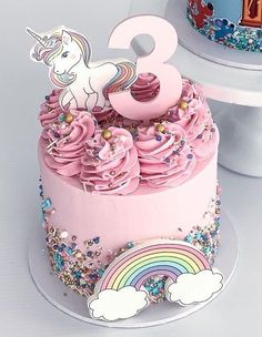 a birthday cake with pink frosting and a unicorn topper on the number three