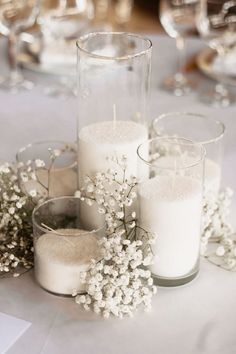 some candles are sitting on a table with flowers and other items around it in glass vases