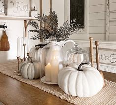 white pumpkins and candles sit on a table