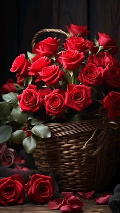 a basket filled with red roses sitting on top of a wooden table next to other flowers