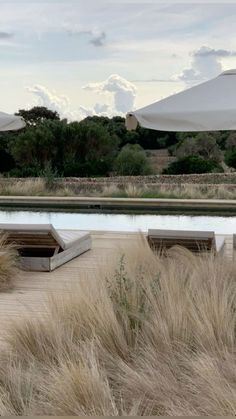 an outdoor seating area with large umbrellas in the background and dry grass on the ground