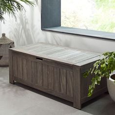 a wooden box sitting on top of a floor next to a plant in a pot